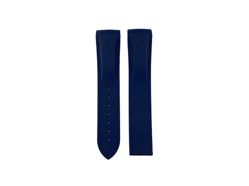 May include: Two navy blue watch straps. One strap has several holes for adjustment and a pointed end. The other strap is a solid piece. Both straps are made of a smooth material.