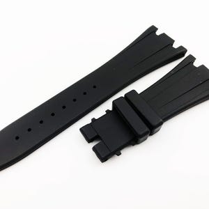 May include: Black rubber watch strap with a buckle. The strap has a textured design and is made for a watch with a 22mm lug width.