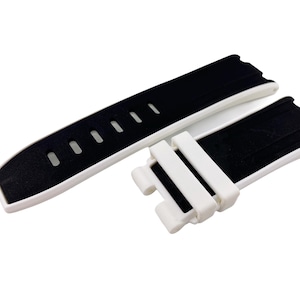 May include: A black and white watch strap with a white buckle and black rubber strap. The strap has a white border and black rubber on the inside.