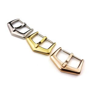 May include: Three watch band buckles in silver, gold, and rose gold. Each buckle has a pointed, arrow-shaped design.