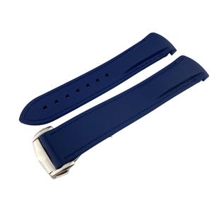 May include: A pair of navy blue watch straps with a silver clasp. The straps are made of a smooth material and feature stitching along the edges. One strap has several holes for adjustment.