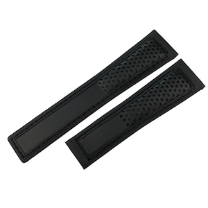 Peut inclure: Deux bracelets de montre noirs. L'un est plus long que l'autre. Les bracelets sont faits d'un matériau texturé avec une série de petits trous. Ils ont un design rectangulaire avec des bords cousus.
