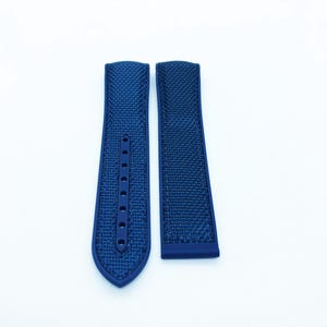 May include: Two navy blue watch straps with a textured pattern. One strap has multiple holes for adjustment. The straps are displayed on a white background.