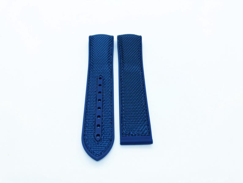 May include: Two navy blue watch straps with a textured pattern. One strap has multiple holes for adjustment. The straps are displayed on a white background.