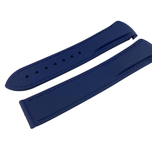 May include: A pair of navy blue watch straps. One strap features adjustment holes, and both have a smooth, slightly glossy finish. The straps are designed to attach to a watch face.