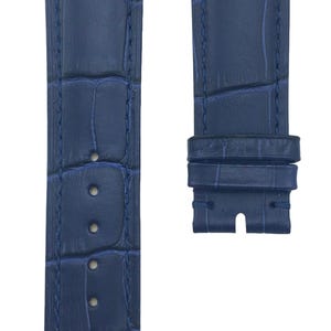 May include: A dark blue alligator-embossed leather watch strap with white stitching. The strap is shown in two parts, the long strap and the buckle.