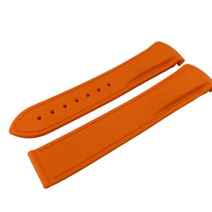 May include: Bright orange watch strap with a stitched edge. The strap has several holes for adjustment and is made of a smooth, solid material. The watch band is a vibrant accessory.