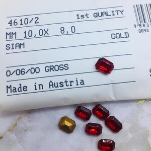 Könnte beinhalten: Eine Sammlung roter und goldener rechteckiger Strasssteine mit einem Papieretikett. Das Etikett lautet "4610/2", "MM 10,OX 8,0", "SIAM", "0/06/00 GROSS", "Made in Austria", "1st QUALITY" und "GOLD".