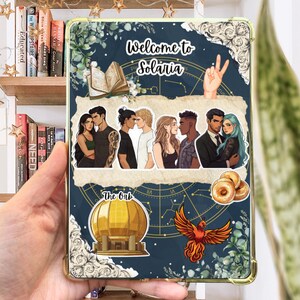 May include: A navy blue tablet case with a gold border, featuring the text "Welcome to Solaria" and illustrations of couples, a phoenix, and a golden orb. The case has a dark blue background with a celestial map design.