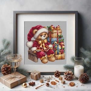 Könnte beinhalten: Ein gerahmtes Kreuzstichbild eines Teddybären in einem Weihnachtsmann-Anzug, der auf einer Bank sitzt, mit verpackten Geschenken dahinter. Der Bär trägt einen roten Anzug mit weißer Bordüre und einen passenden Hut. Die Geschenke sind in braunes, blaues und goldenes Papier mit Bändern verpackt.