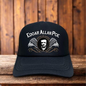 May include: Black trucker hat featuring the name "Edgar Allan Poe" in white, with a portrait and wings design. The hat has a mesh back and a curved brim, suitable for casual wear.