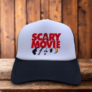 Könnte beinhalten: Schwarze und weiße Trucker-Mütze mit weißer Frontplatte. Auf der Vorderseite steht in Rot das Wort "SCARY MOVIE", zusammen mit einer Grafik einer Pistole, eines Messers und anderer Gegenstände. Die Mütze hat einen gebogenen Schirm.