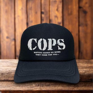 Puede incluir: Gorra de camionero negra con texto blanco que dice "COPS" y "Watcha gonna do when they come for you..."