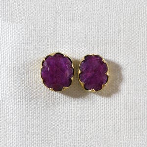 May include: A pair of gold earrings with purple gemstone settings. The gemstones are carved with a floral design.