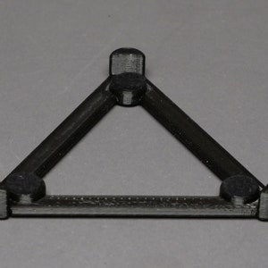 May include: A black triangular stand with three round felt pads on the bottom.