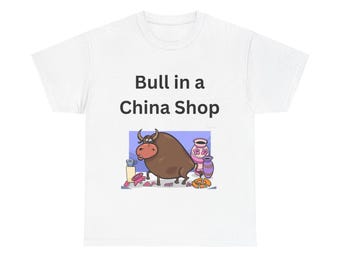 May include: White t-shirt featuring a cartoon bull in a china shop design. The bull is brown with horns, surrounded by broken pottery and other items. The text "Bull in a China Shop" is above the illustration.