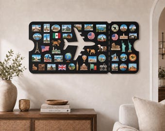 May include: A black, ticket-shaped wall display board featuring a central airplane cutout. The board is covered in numerous colorful, small souvenir magnets depicting various global landmarks, national flags, animals, and travel-themed icons.