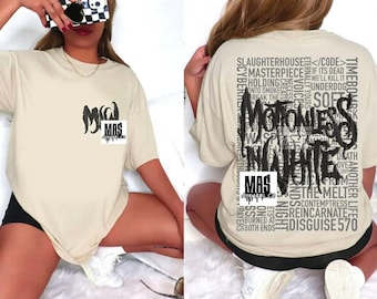 May include: Beige short-sleeved t-shirt with a front pocket design and a large graphic on the back. The back graphic features the words "Motionless in White" in a gothic font, surrounded by other text. The front pocket has the letters "MAS" and a logo.