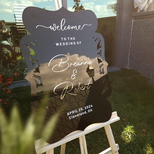 Letrero de bienvenida para boda de acrílico negro con letras doradas modernas.