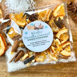 May include: A clear plastic bag filled with Winter Vanilla Coconut simmer potpourri, containing dried orange slices, cinnamon sticks, star anise, and coconut flakes. A round label features the text: Winter Vanilla Coconut SIMMER POTPOURRI. Empty ingredients into pot with 3 cups of water, simmer on low, add water as needed. STONEHOUSEBOTANICALS.ETSY.COM.