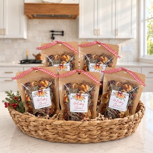 May include: Five brown kraft paper pouches filled with dried fruit, pine needles, and berries, each tied with a red and white gingham ribbon. A white label on each pouch features the text Holiday Cheer and a graphic of orange slices.