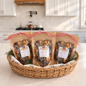 May include: Three clear pouches of simmer potpourri containing dried orange slices, pine needles, and berries, each tied with a red and white gingham ribbon. Each pouch features a label with the text Holiday Cheer Simmer Potpourri.