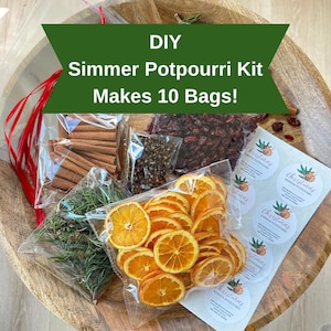 May include: DIY Simmer Potpourri Kit with ingredients like dried orange slices, cinnamon sticks, and rosemary. The kit makes 10 bags and includes Christmas-themed stickers. The ingredients are packaged in clear bags and arranged on a wooden tray.