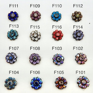 May include: A collection of floral-shaped embellishments with various colors, including blue, red, purple, and clear. Each embellishment has a central stone surrounded by smaller stones. The product codes F101 through F116 are visible.