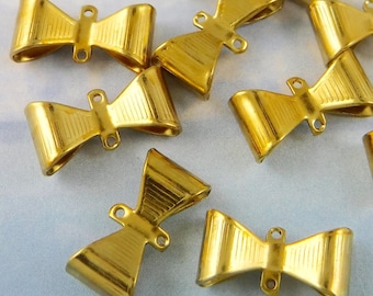 May include: A collection of gold-colored metal bow-shaped clasps. Each clasp has a ribbed texture on the bow and small loops on the ends. These clasps are likely used for jewelry making or crafting.