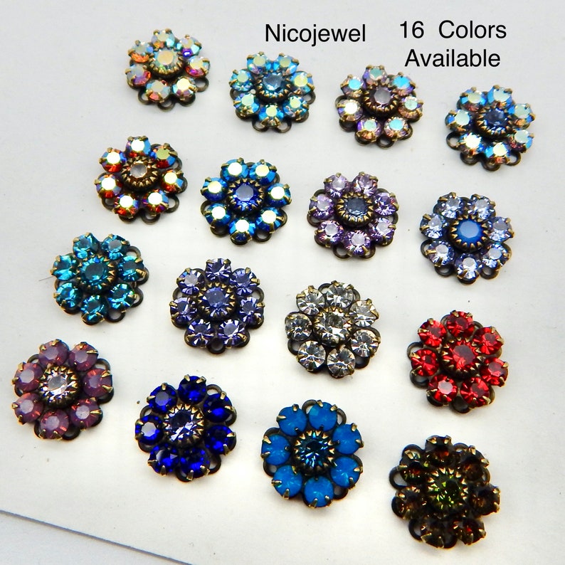 May include: A collection of sixteen flower-shaped rhinestone embellishments in various colors. Each jewel has a central stone surrounded by petals of smaller rhinestones. The text "Nicojewel" and "16 Colors Available" are visible.