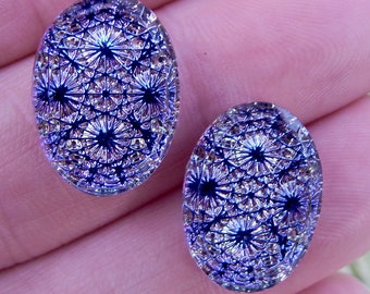May include: Two oval-shaped glass cabochons featuring a deep blue and iridescent purple geometric starburst pattern. The surface of each piece is smooth and reflective, displaying a repeating intricate lattice design throughout.