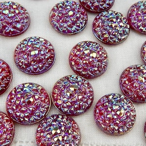 May include: A collection of iridescent, round buttons with a textured, faceted surface. The buttons are primarily a deep red color with hints of purple and gold, creating a shimmering effect. These decorative buttons are ideal for sewing and craft projects.