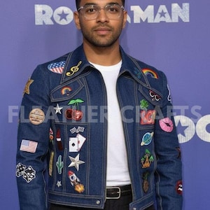 May include: A denim jacket with colorful embroidered patches, including a rainbow, a cherry, and a rocket. The jacket has a classic collar and a button-up front. The patches add a unique, artistic flair to the jacket.