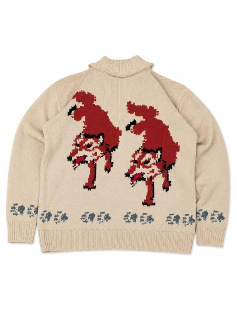May include: A beige knit sweater featuring a high collar and long sleeves. The back displays two pixelated red and black wolf figures, with a repeating pattern of small dark blue paw prints along the bottom hem of the garment.