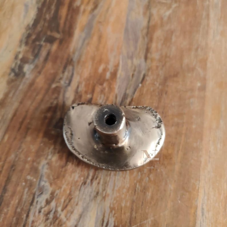 Puede incluir: Un tirador de armario de color bronce con una forma irregular &uacute;nica. El tirador presenta un poste cil&iacute;ndrico central y una cara ovalada texturizada. Este herraje est&aacute; dise&ntilde;ado para muebles y a&ntilde;ade un toque de encanto vintage.