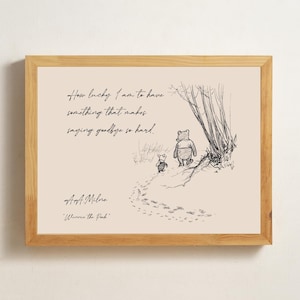 May include: A framed print with a pen and ink illustration of Winnie the Pooh and Piglet. The quote "How lucky I am to have something that makes saying goodbye so hard" is written above the illustration. The print is in a wooden frame.