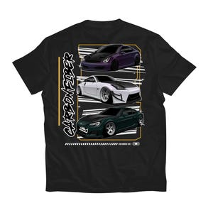 May include: Black t-shirt with a graphic design of three cars. The cars are a purple Nissan 350Z, a white Nissan 240SX, and a green Subaru BRZ. The text "CARBON FIBER" is written vertically on the left side of the graphic.