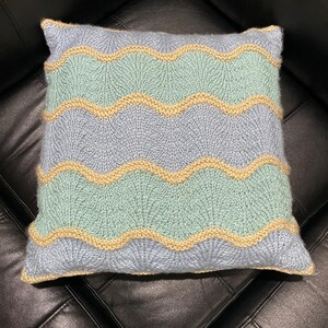 May include: A blue and green knitted pillow with a wavy pattern and a yellow accent.