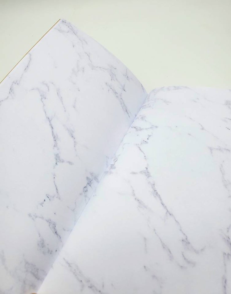 May include: An open notebook with a white marble pattern on the cover and pages.