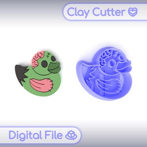 Puede incluir: Un cortador de arcilla de pato zombi verde y rosa y un cortador de arcilla con forma de pato azul. El pato zombi tiene un cerebro, puntadas y un ala negra. El texto "Clay Cutter" y "Digital File" están en la imagen.