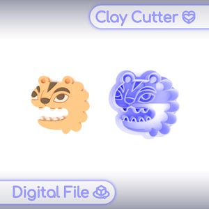 May include: Two clay cutters in the shape of a tiger's head. One is orange with brown stripes and the other is blue. The cutters have a jagged edge and open mouths. The text "Clay Cutter" and "Digital File" are in the image.