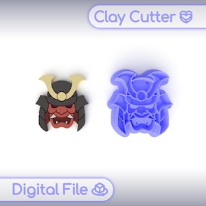 Puede incluir: Un cortador de arcilla y una pieza de arcilla terminada con forma de máscara de samurái japonés. La pieza terminada es roja, negra y dorada. El cortador es azul. El texto "Clay Cutter" y "Digital File" están en la imagen.