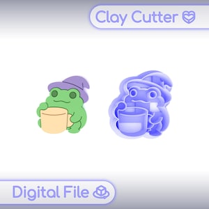 May include: A digital file for a clay cutter featuring a green frog wearing a purple witch hat and holding a beige mug. The design includes a colourful illustration of the frog and a corresponding blue outline shape for the cutter, with the text Clay Cutter.