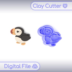 May include: A digital file featuring a clay cutter and a finished clay model of a puffin bird. The puffin has a black back, white belly, orange beak, and tan feet. The clay cutter is blue and shaped like the bird.