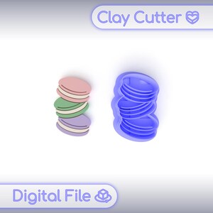 Puede incluir: Un cortador de arcilla azul y un modelo de arcilla colorido de macarons. El cortador tiene forma de macarons apilados. El modelo tiene capas rosas, verdes y moradas. El texto "Clay Cutter" y "Digital File" son visibles.