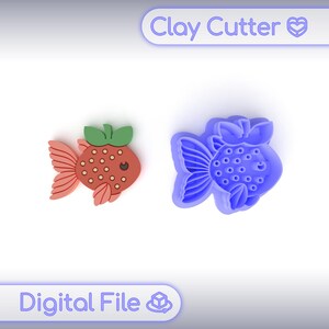 Può includere: Un tagliapasta blu e una figura di argilla finita di un pesce rosso. La figura finita è rossa, marrone e verde. Il testo "Clay Cutter" e "Digital File" è nell'immagine.