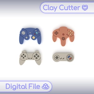 May include: Four colourful clay cutters shaped like video game controllers. The controllers are blue, brown, and grey. The text "Clay Cutter" and "Digital File" are at the top and bottom of the image.