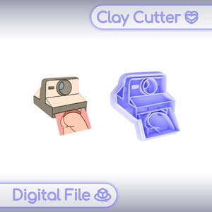 May include: Two clay cutters: one is a tan and gray camera with a pink image, the other is a blue camera-shaped cutter. The text "Clay Cutter" and "Digital File" are in the image.