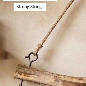 May include: A natural wooden branch suspended by a twisted jute string attached to a dark metal hook. The text "Beautiful & Robust Hooks" and "Strong Strings" is visible. The branch features additional small metal hooks for hanging items.