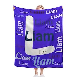Puede incluir: Una manta de forro polar morada con el nombre "Liam" repetido en varias fuentes y colores.